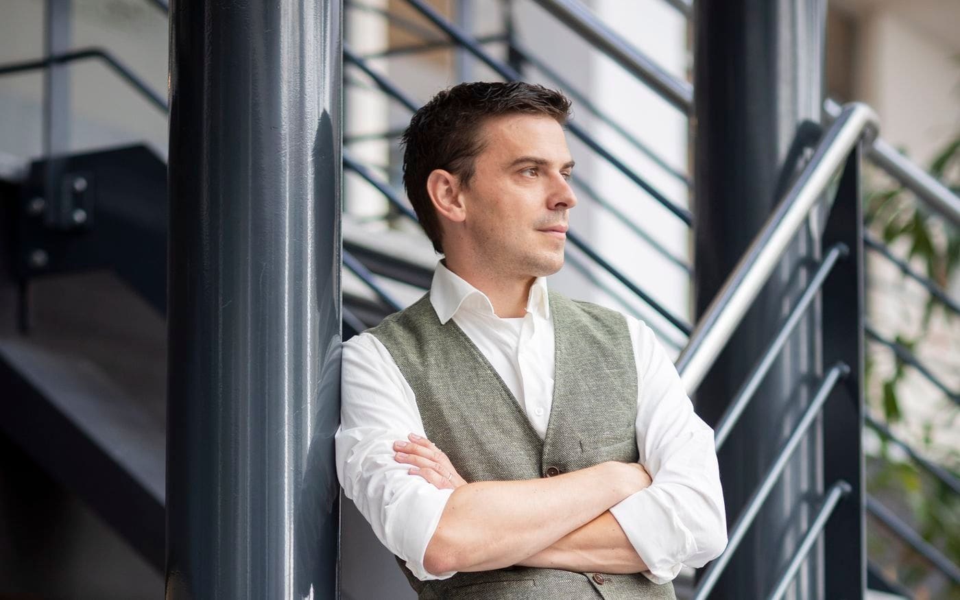 Ondernemer staat ontspannen tegen de trapleuning in het kantoorpand
