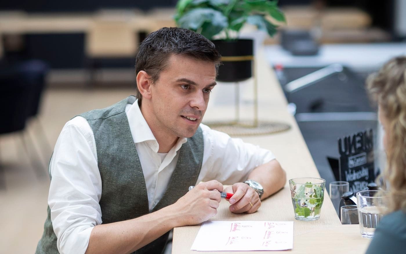 Adviseur licht iets toe met aantekeningen aan de statafel