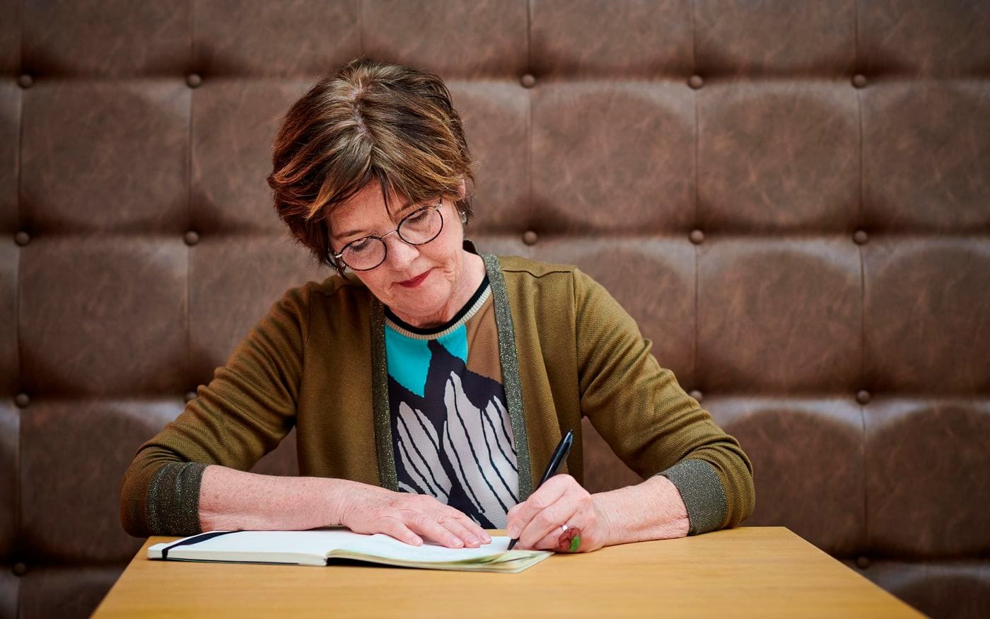 Vrouw maakt aantekeningen in een notitieboek aan tafel