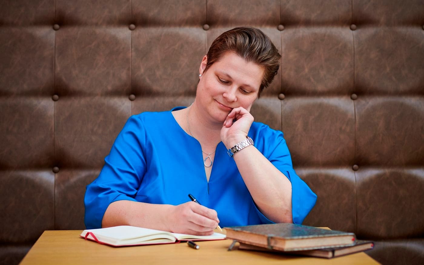 Vrouw schrijft iets op en denkt na aan tafel