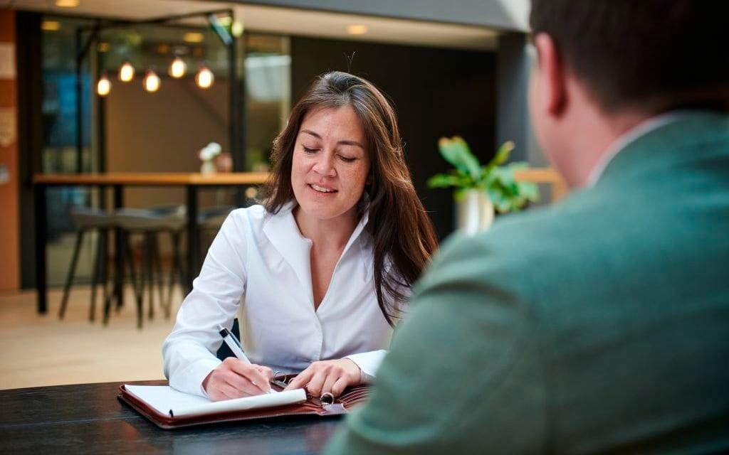 Onderneemster maakt aantekeningen tijdens een gesprek aan tafel