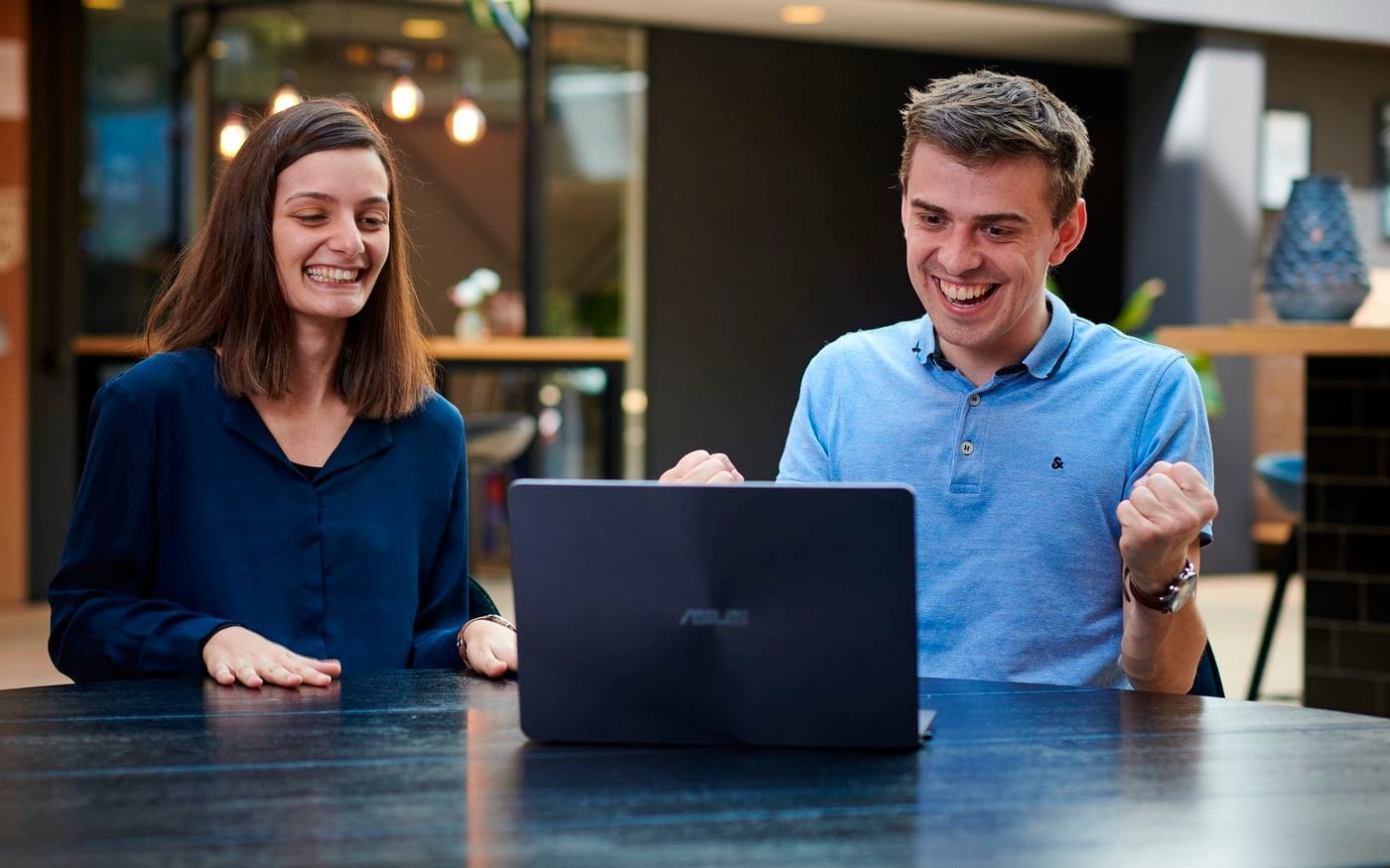 Twee mensen kijken samen glimlachend naar een laptop