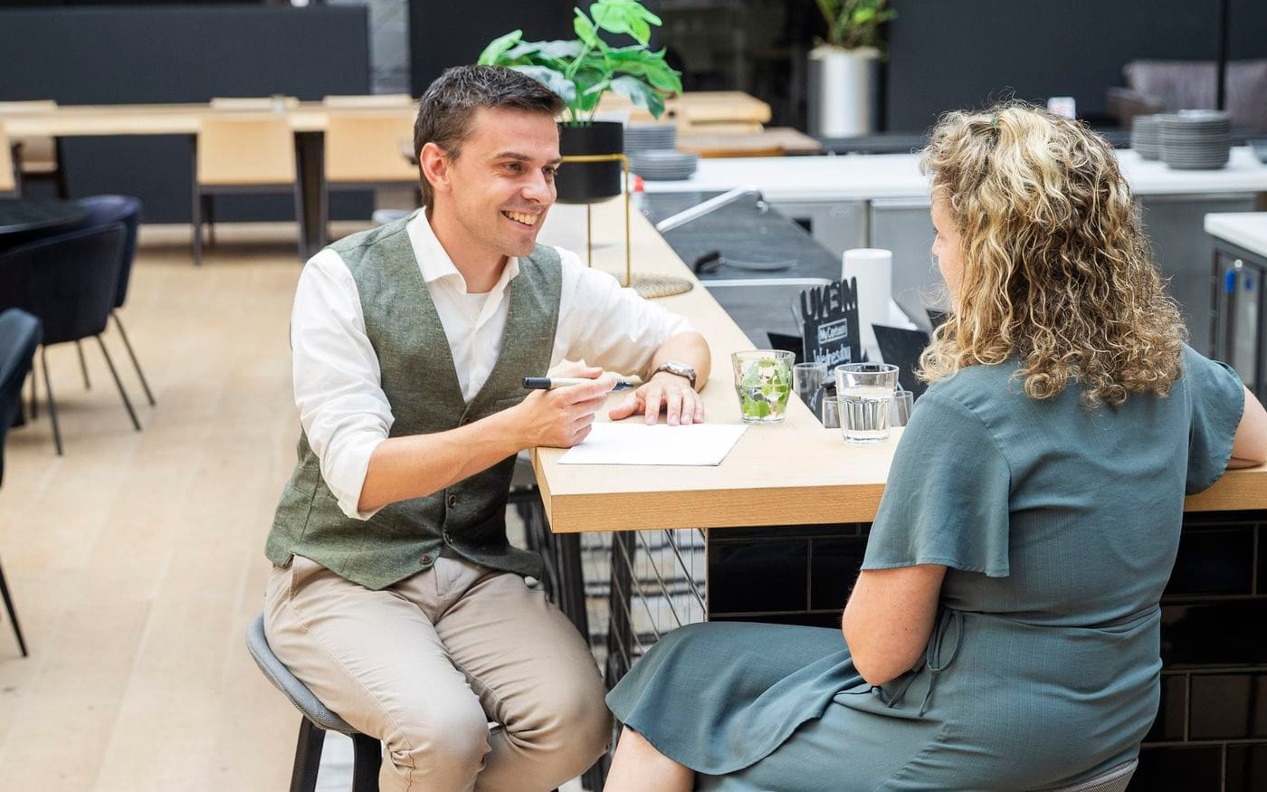 Adviseur en onderneemster overleggen aan de statafel