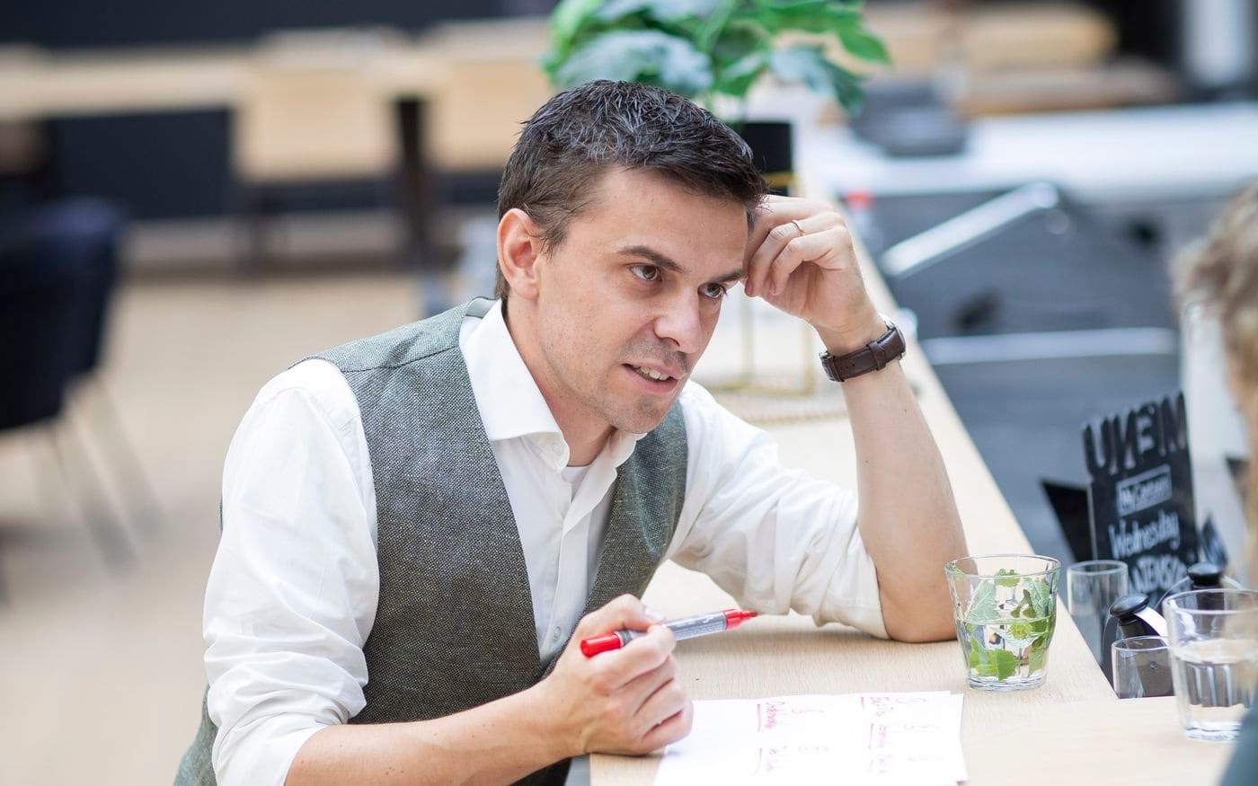 Adviseur denkt na met een pen in de hand aan de statafel