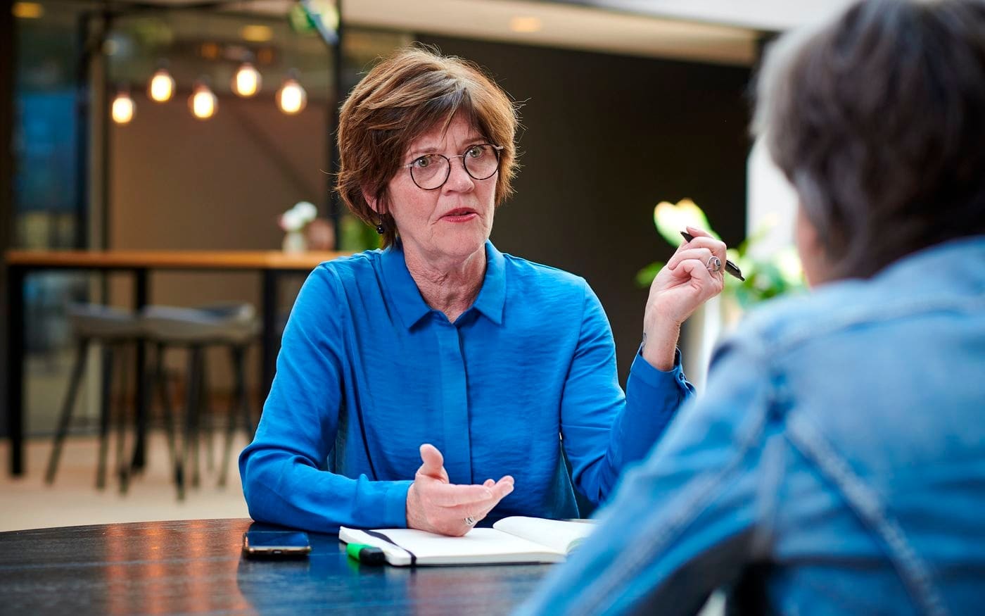 Vrouw legt iets uit tijdens een gesprek aan tafel