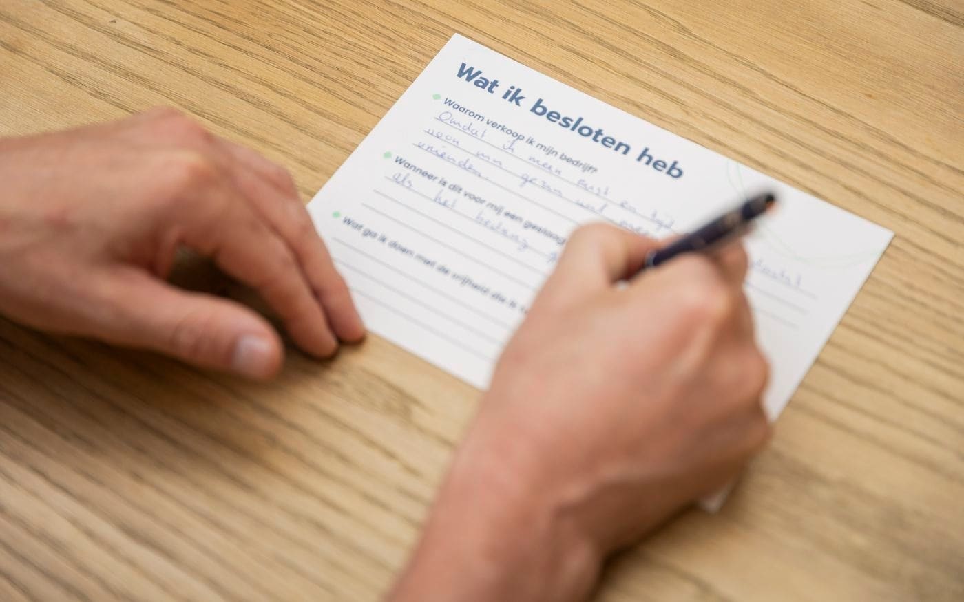 Hand met pen boven een formulier op tafel